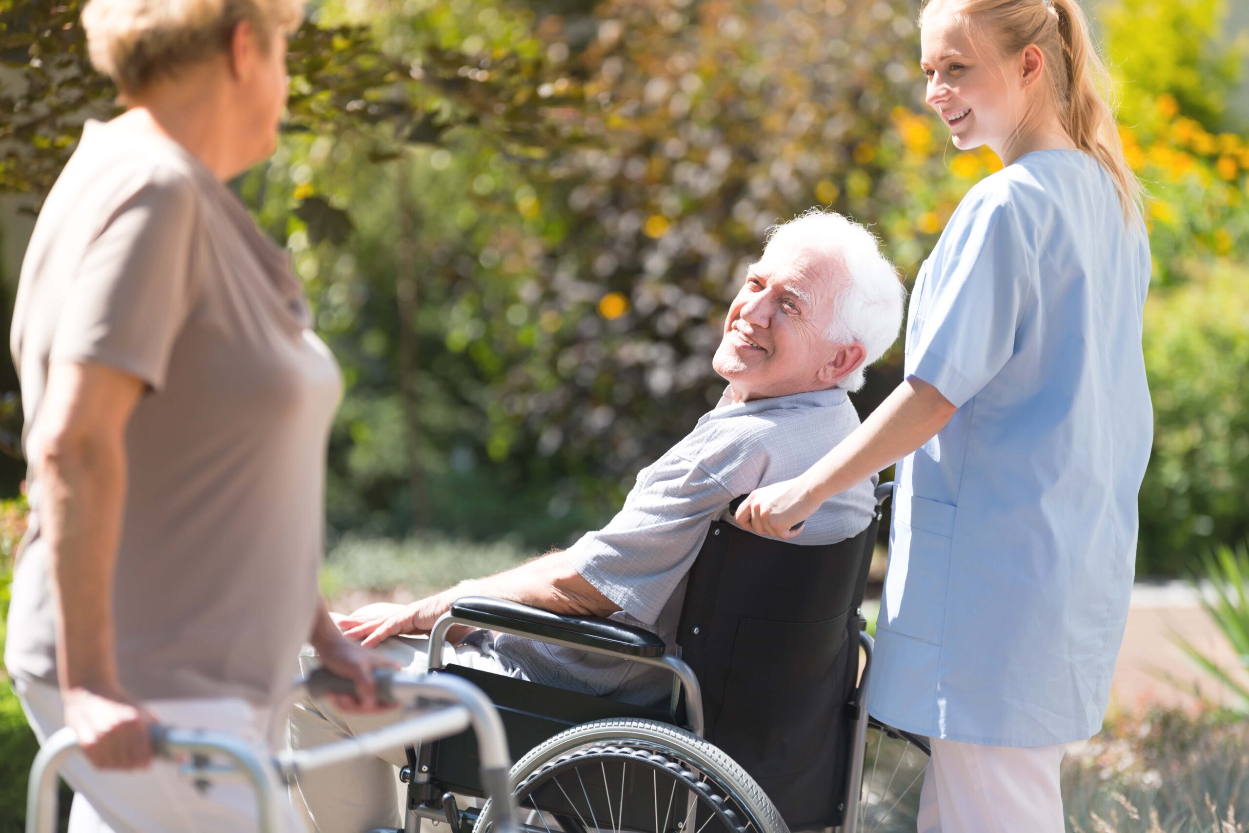 Group of friends two elderly and one nurse outside on a walk, chatting as they cross paths.